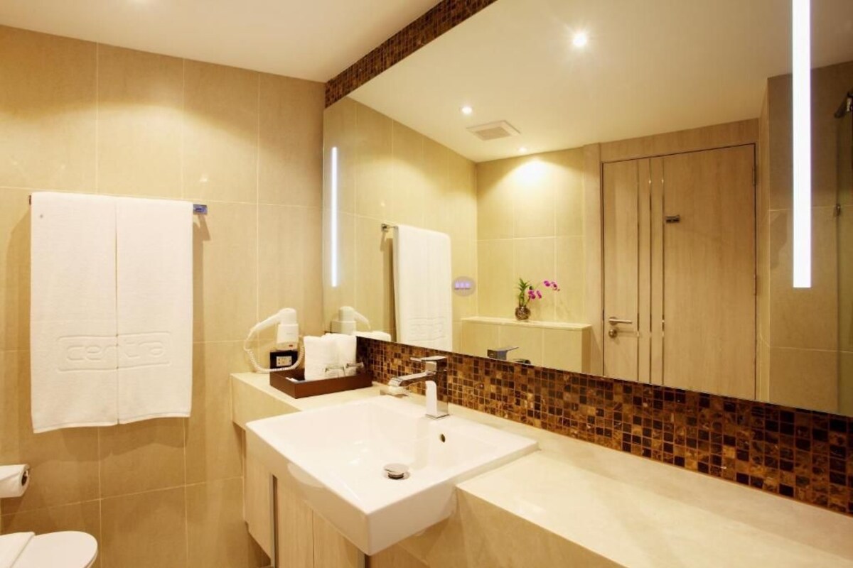 A modern bathroom with a large mirror, two sinks, and a shower area.