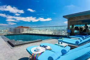 A rooftop pool area with blue lounge chairs, a small pool, and a glass balustrade. - SHILAT Avenue Pattaya Hotel (Pattaya)