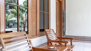 A wooden bench and table set against a wall with large windows. - Bendesa Accommodation (Kuta)