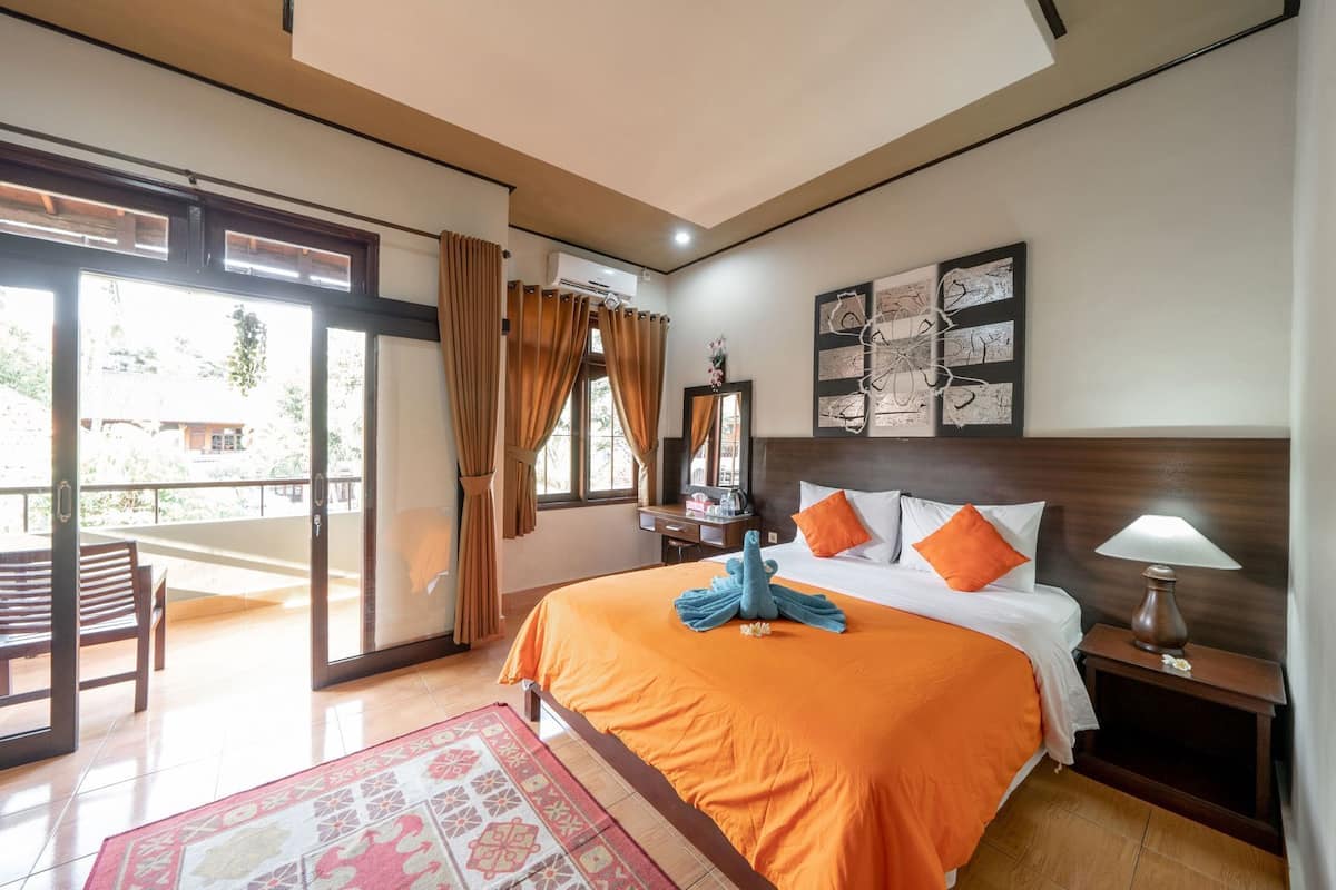 A hotel room with a bed, a desk, a chair, a nightstand, and a window with curtains.