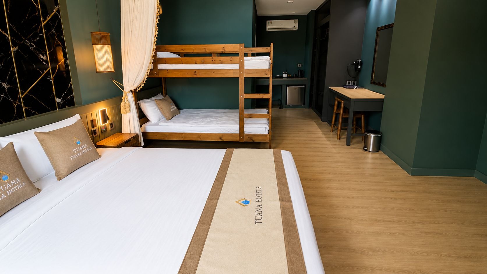 A hotel room with a bunk bed, a desk, and a kitchenette.