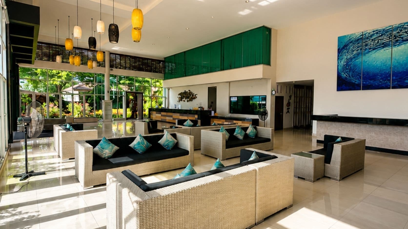 A spacious lobby with wicker sofas, a reception desk, and a large abstract painting on the wall.