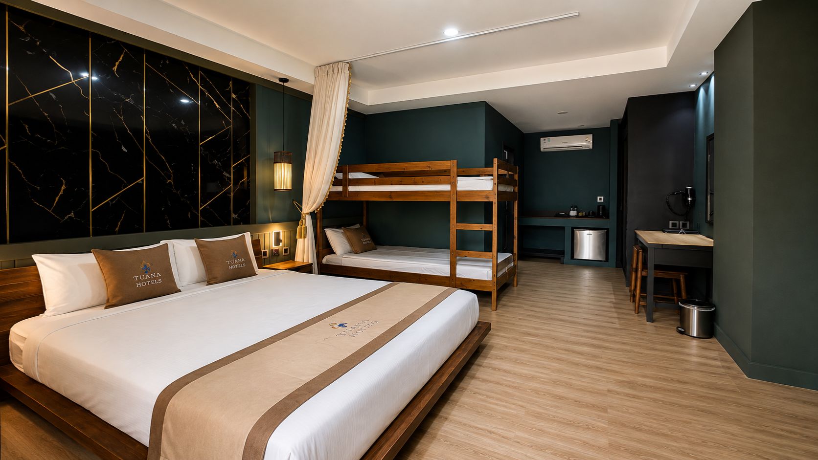 Une chambre d’hôtel avec un grand lit, un plus petit lit, un bureau et une kitchenette.