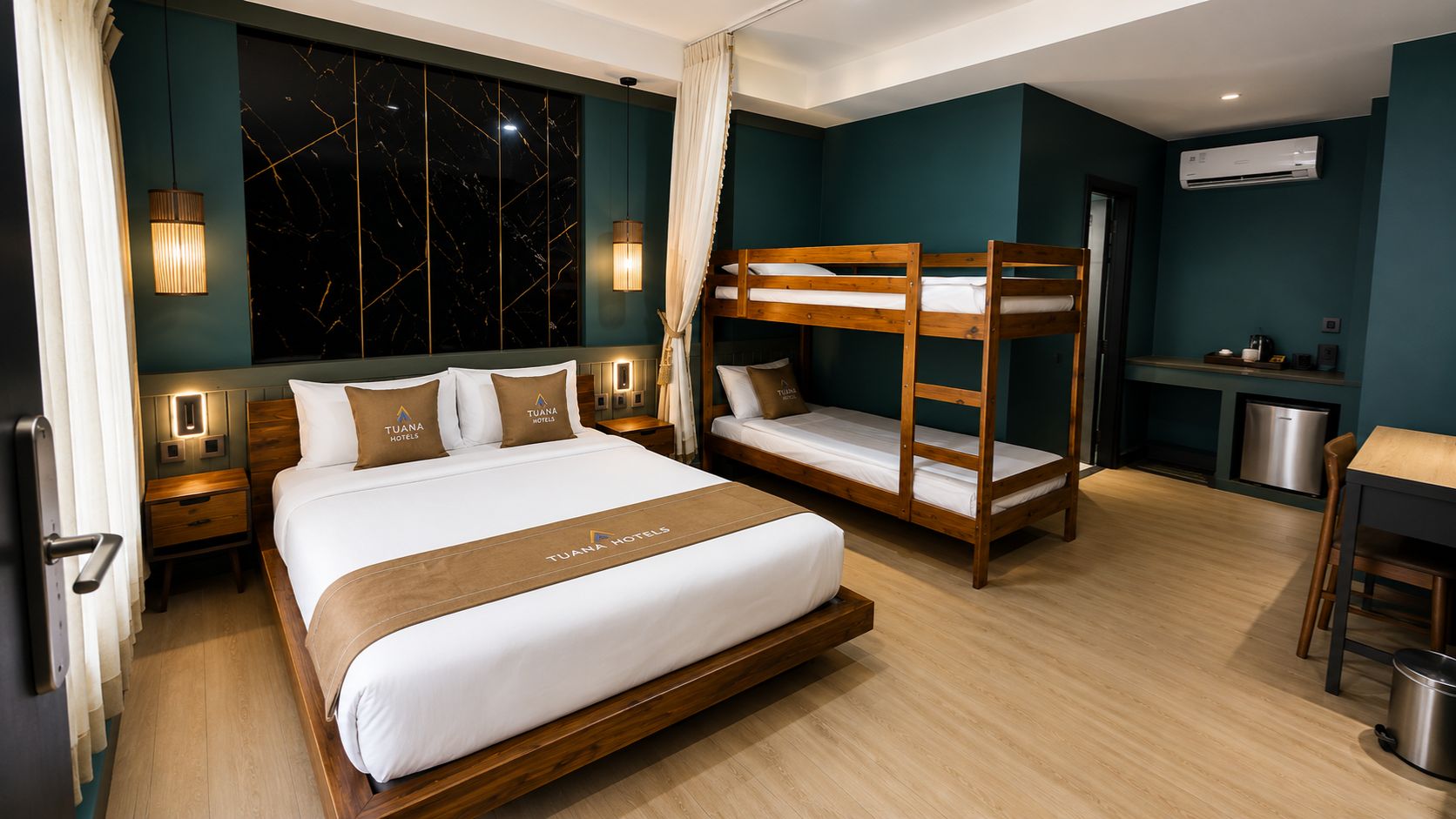 A hotel room with a large bed, a bunk bed, a desk, and a kitchenette.