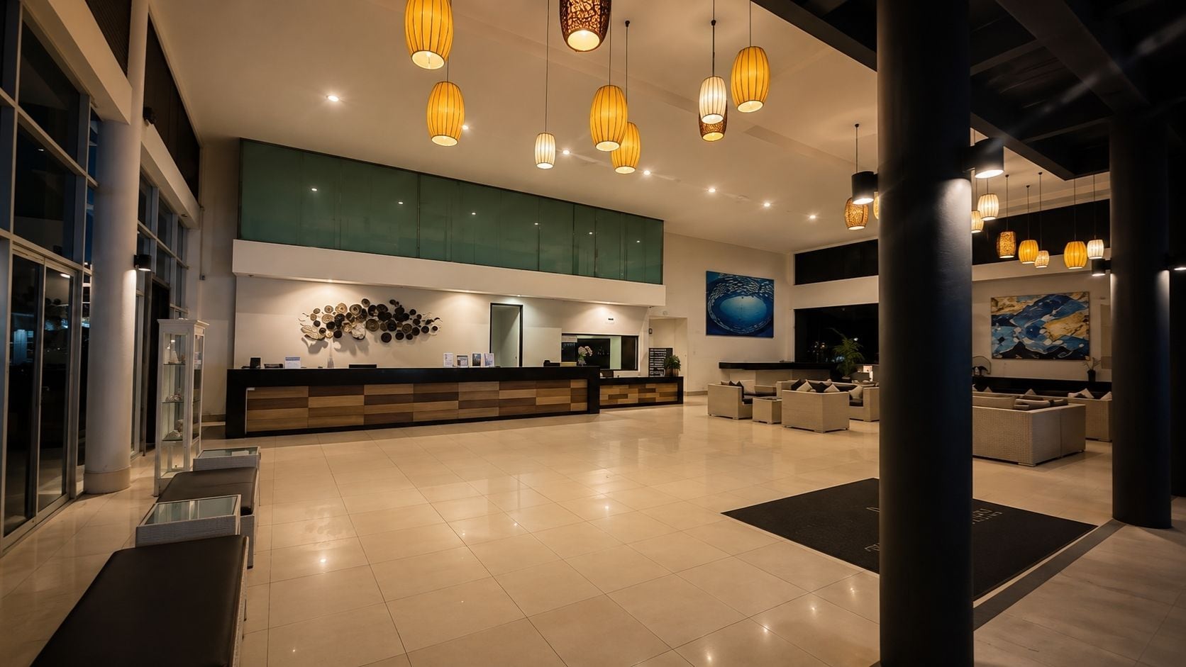 A spacious lobby with a reception desk, seating area, and artwork on the walls.
