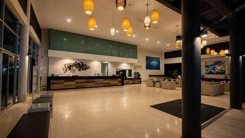 A spacious lobby with a reception desk, seating area, and artwork on the walls.