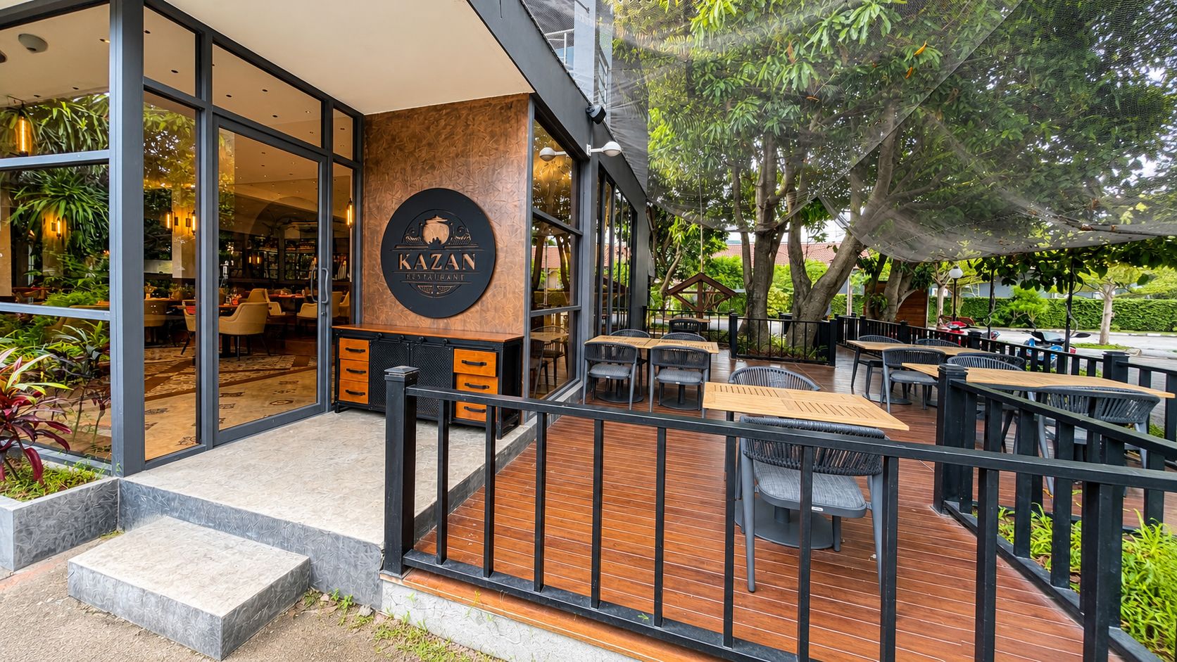 An outdoor seating area with tables and chairs, a wooden deck, and a restaurant sign.