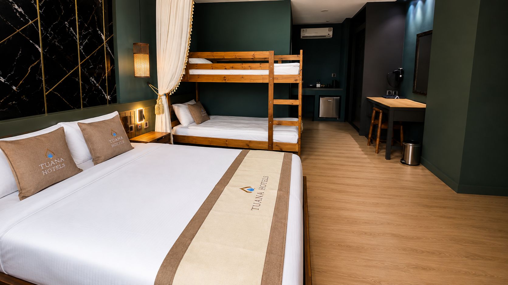 A hotel room with a large bed, a smaller bed, a desk, and a kitchenette.