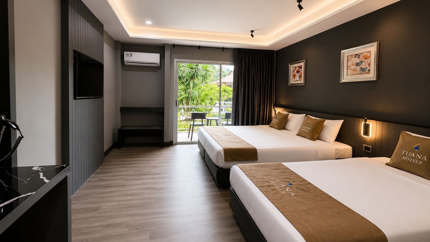 A hotel room with two beds, a desk, a TV, and an air conditioning unit.