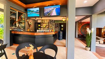 A bar area with a counter, seating, and a television screen displaying a scenic view.