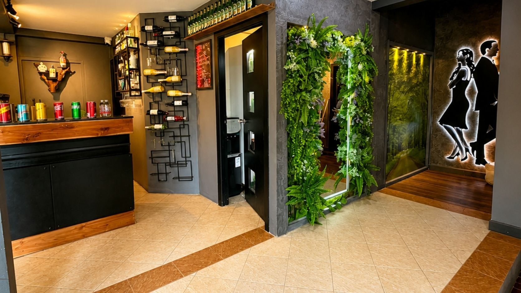 Una hall d'albergo con una reception, bottiglie di vino, una parete decorata con piante e un murale.