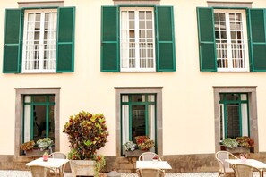 Stylish building with green shutters and potted plants.