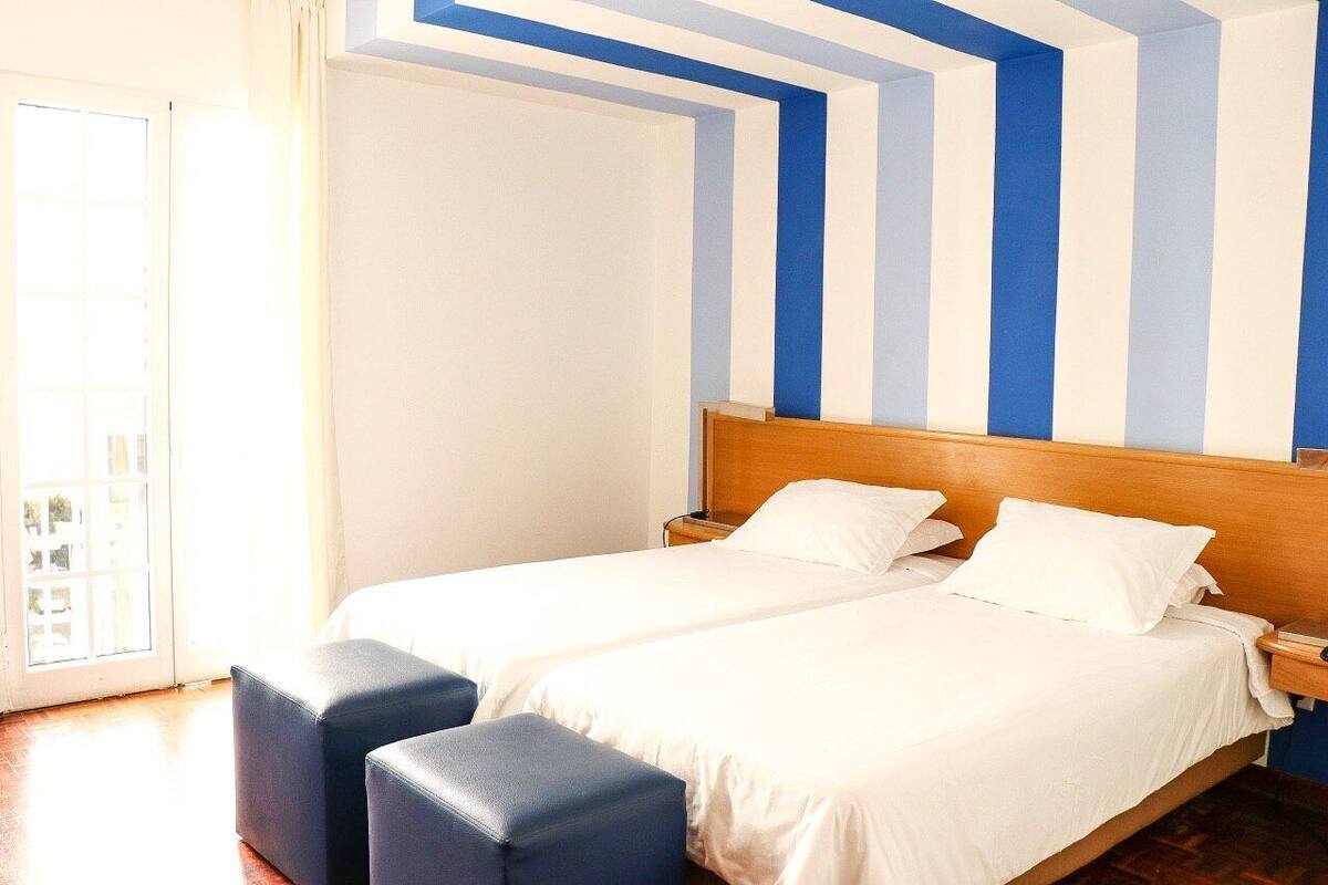 A hotel room with two beds, a wooden headboard, and a large window with a view.
