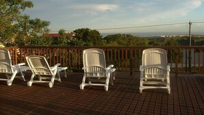 A deck with white plastic lounge chairs facing a scenic view. - Sunnyridge Lodge (East London)