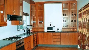 A kitchen with wooden cabinets, a stove, and a microwave. - Sunnyridge Lodge (East London)