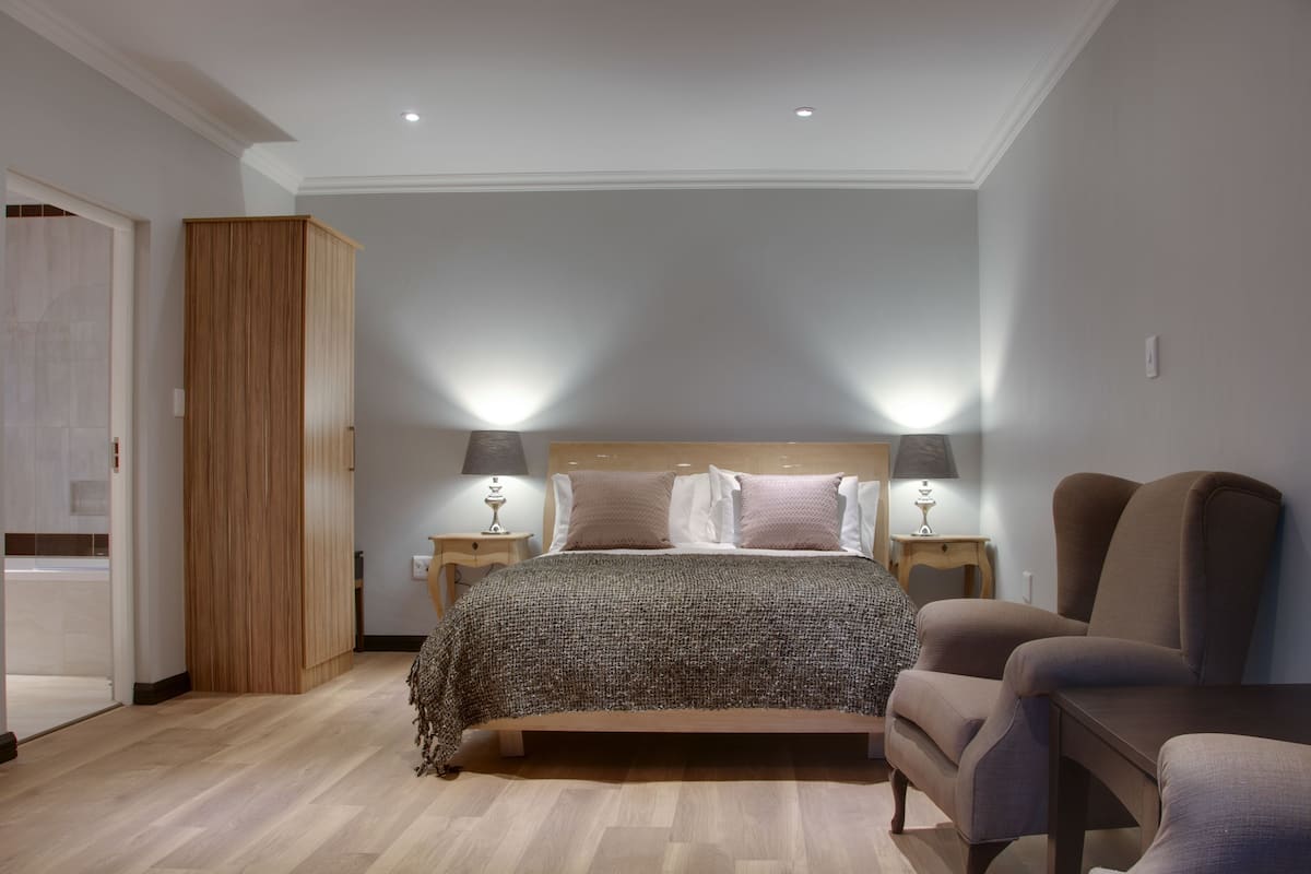 Quarto com uma cama, duas luminárias de cabeceira, um guarda-roupa de madeira e uma cadeira.