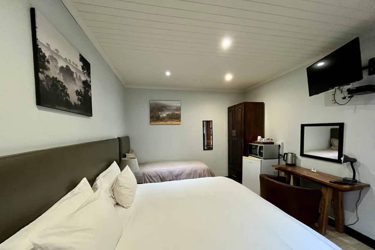 Quarto de hotel com uma cama grande, uma escrivaninha com cadeira, televisão, micro-ondas e armários.
