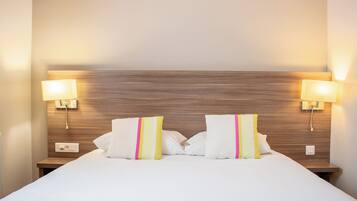 Une chambre d’hôtel avec un grand lit, deux lampes de chevet et une tête de lit en bois.