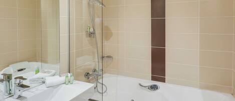 A modern bathroom with a white bathtub, a glass-enclosed shower, and a sink with toiletries.