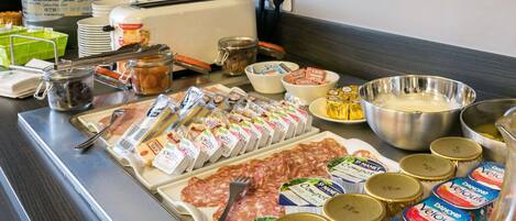 A buffet with various food items including meats, cheeses, and condiments.
