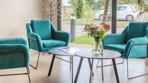 Un interior moderno con sillas color turquesa, una mesa redonda y un florero con flores.