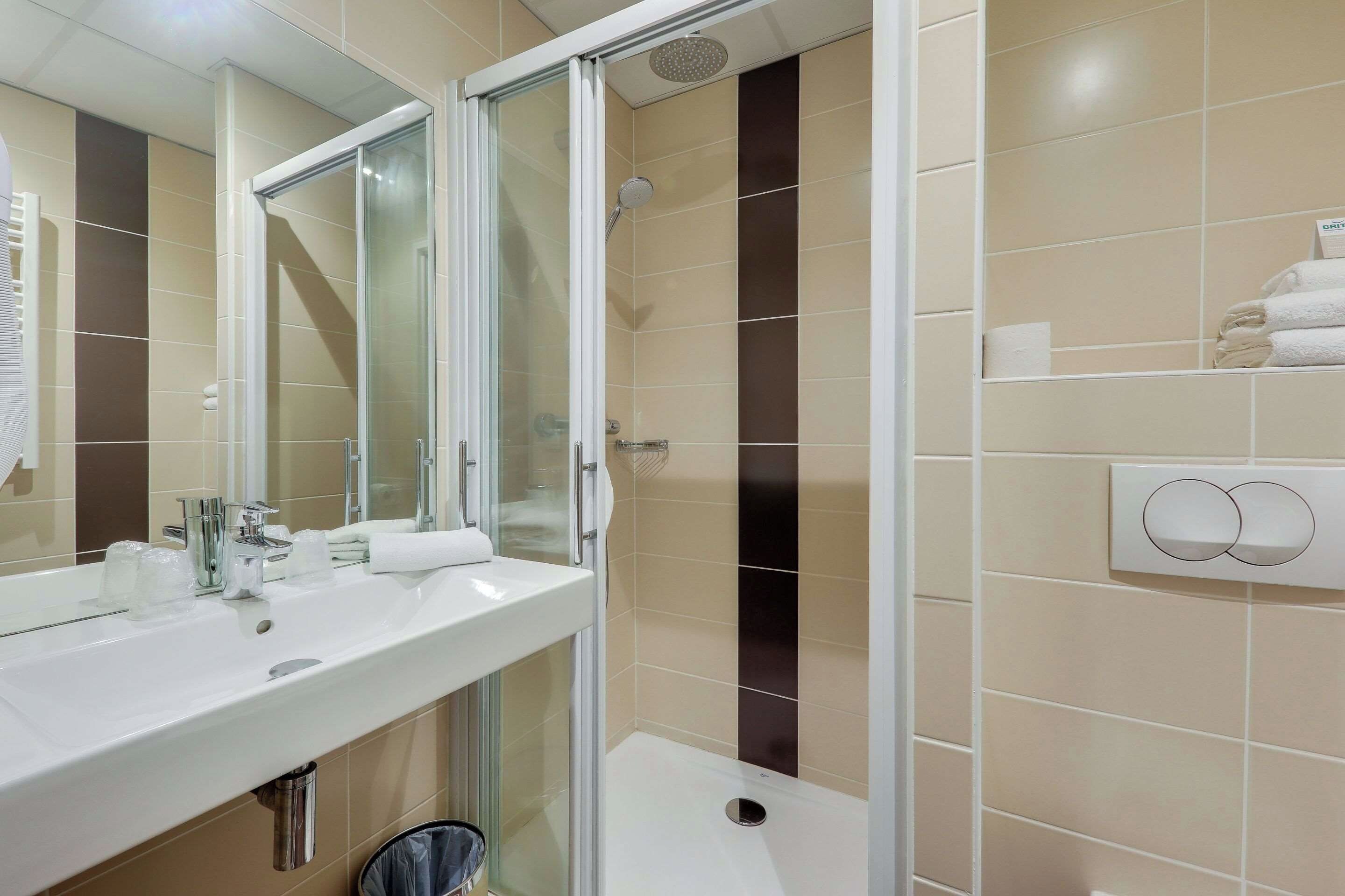 A modern bathroom with a glass-enclosed shower, a white sink, and a towel rack.