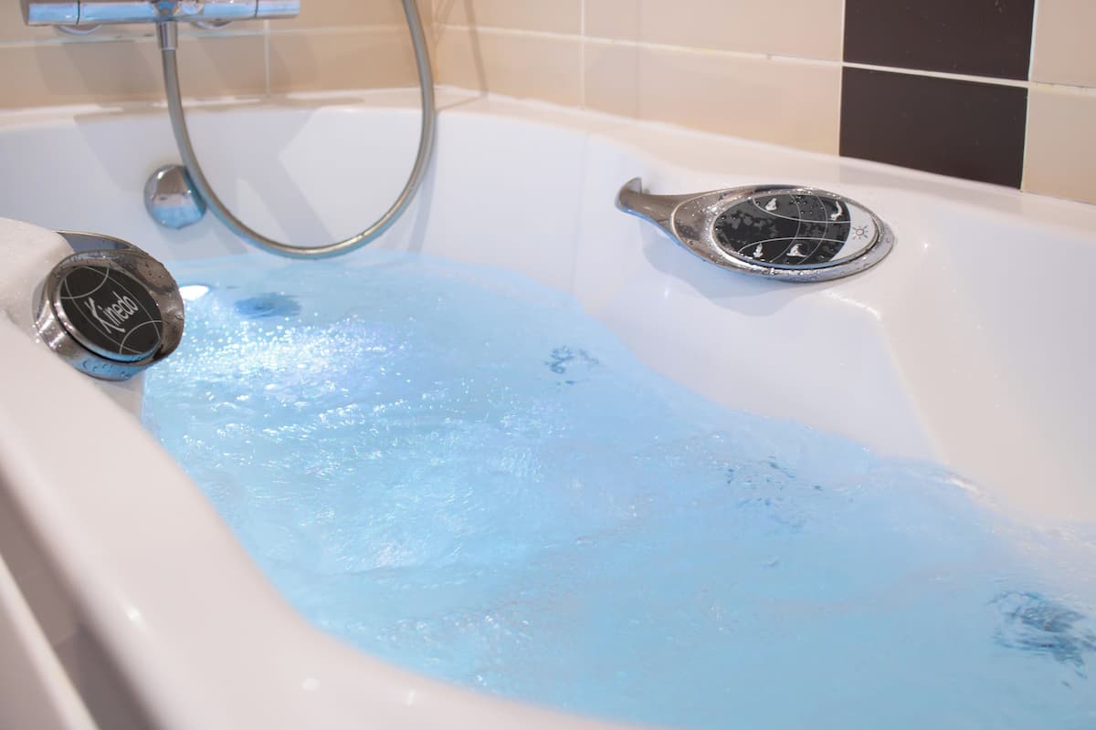 A bathtub with a handheld showerhead and a built-in drain.