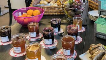 Una mesa con botes de conservas variados y una cesta de frutas.