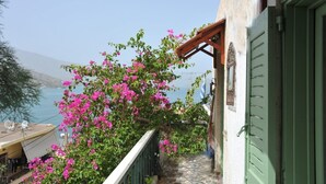 A balcony with a view of the sea, a wooden pergola, and a building with green shutters. - Elounda Apartments (Agios Nikolaos)