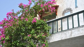 A building with a balcony and a tree with pink flowers. - Elounda Apartments (Agios Nikolaos)