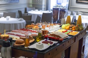 Un bufé con diversas opciones de comida, incluyendo carnes, quesos, frutas y pasteles.