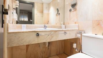 A modern bathroom with a marble sink, a towel rack, a toilet, and a mirror.