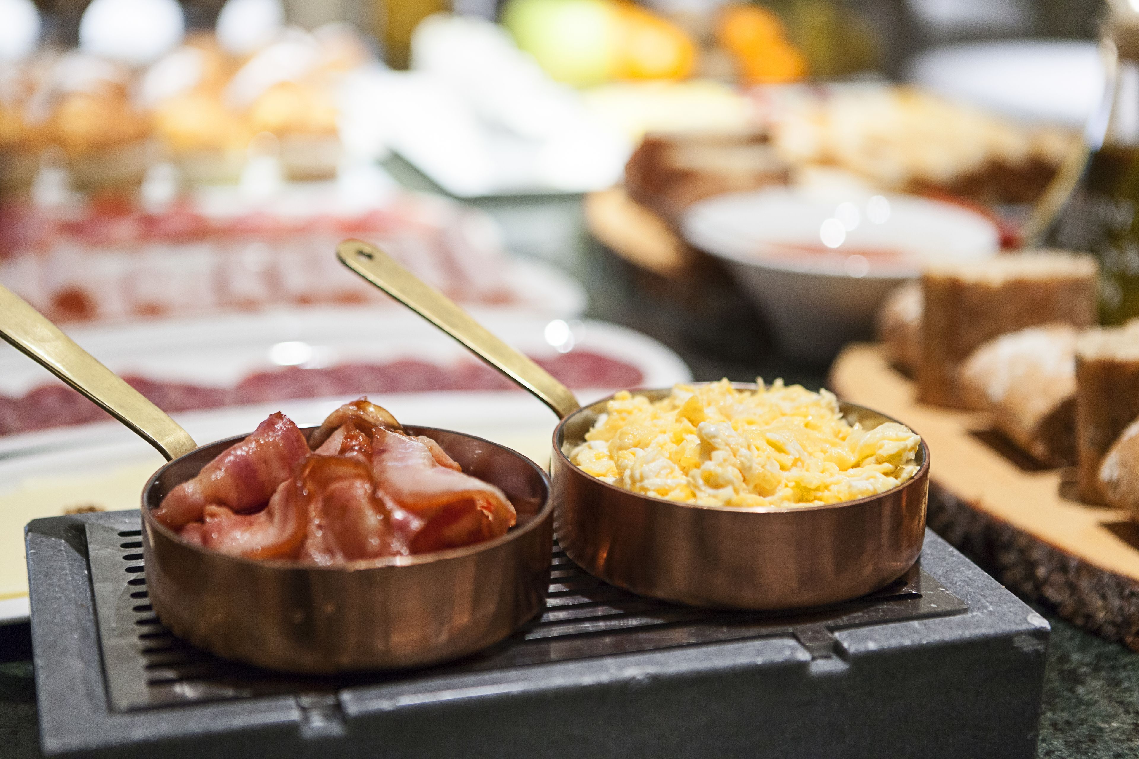 Un bufé con diversos platos, incluyendo huevos revueltos y tocino.