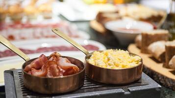 Un bufé con diversos platos, incluyendo huevos revueltos y tocino.
