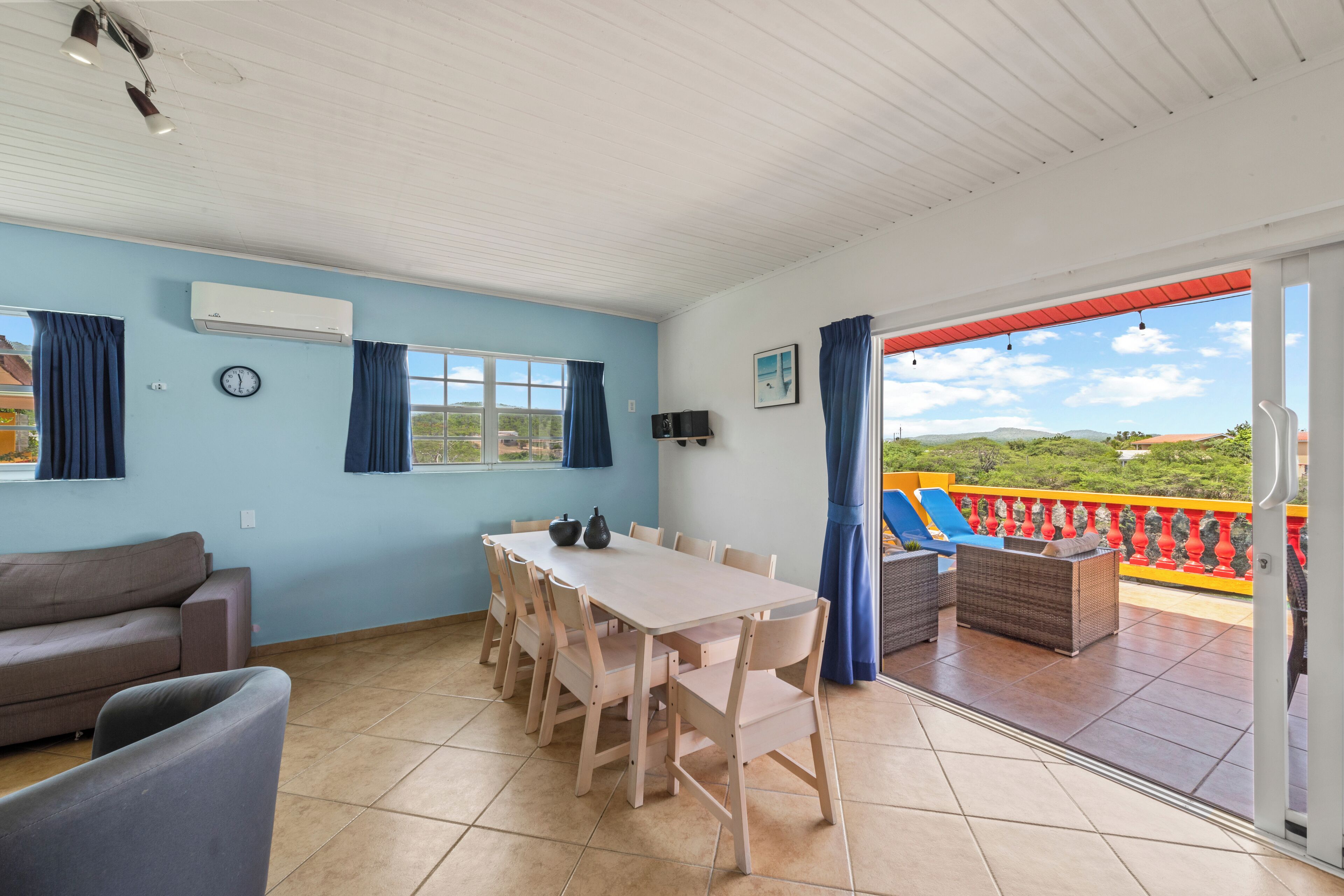 Una habitación con una mesa de comedor, sillas, un sofá y un balcón con vistas.
