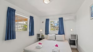 Una habitación de hotel con una cama grande, dos mesitas de noche y un ventanal con cortinas.