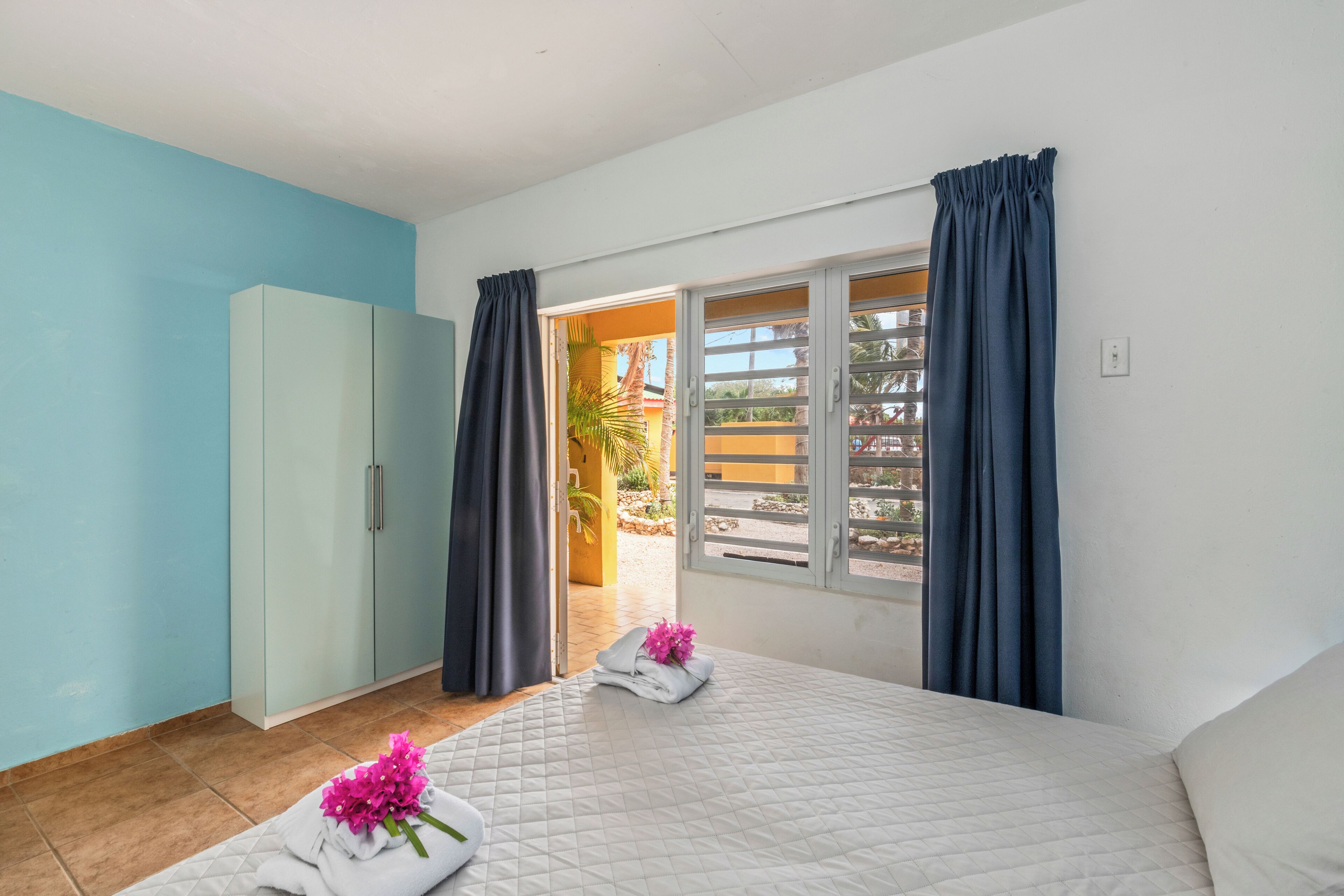 A bedroom with a bed, a wardrobe, and a window with curtains.