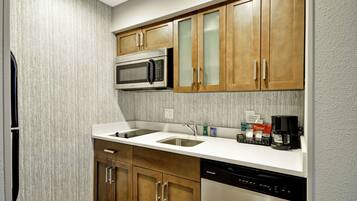 A modern kitchen with wooden cabinets, a stainless steel microwave, a double sink, and a dishwasher.