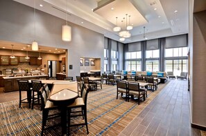 A spacious hotel lobby with a large seating area, a kitchen, and a view of the outdoors. - Homewood Suites by Hilton Cincinnati/West Chester (West Chester)