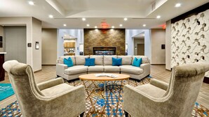 A modern hotel lobby with a curved sofa, a coffee table, and two armchairs. - Homewood Suites by Hilton Cincinnati/West Chester (West Chester)