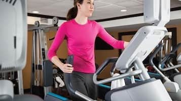 A person using a treadmill in a gym with various exercise equipment.