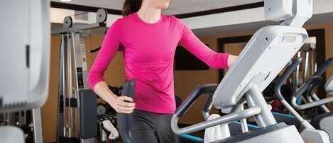 A person using a treadmill in a gym with various exercise equipment.