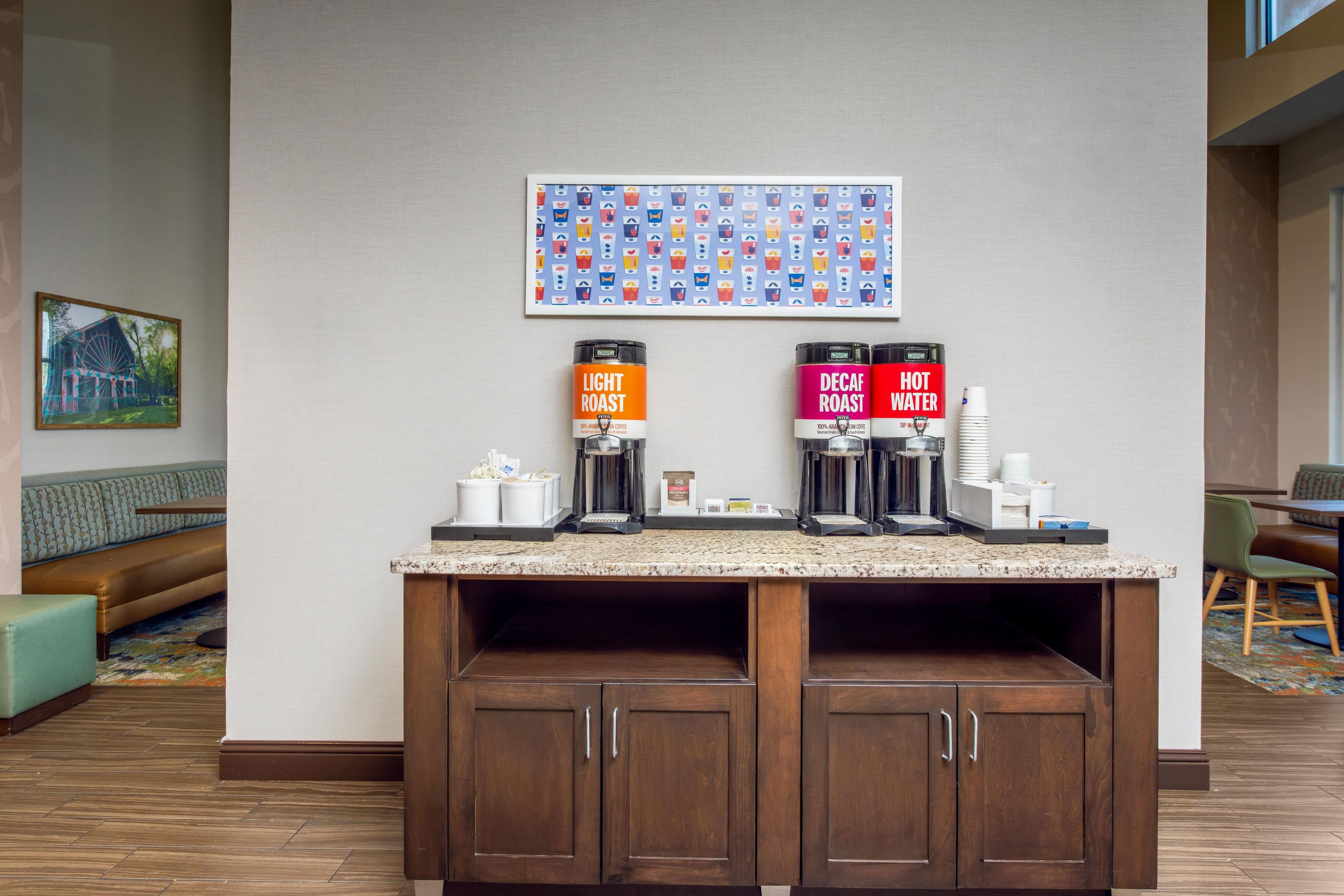 A coffee station with two coffee dispensers labeled 'Light Roast' and 'Decaf Roast' and a 'Hot Water' dispenser.