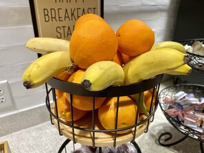 Een fruitmand met bananen en sinaasappels op een aanrecht.
