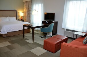 Habitación de hotel con cama, escritorio con silla, televisor y una mesita.