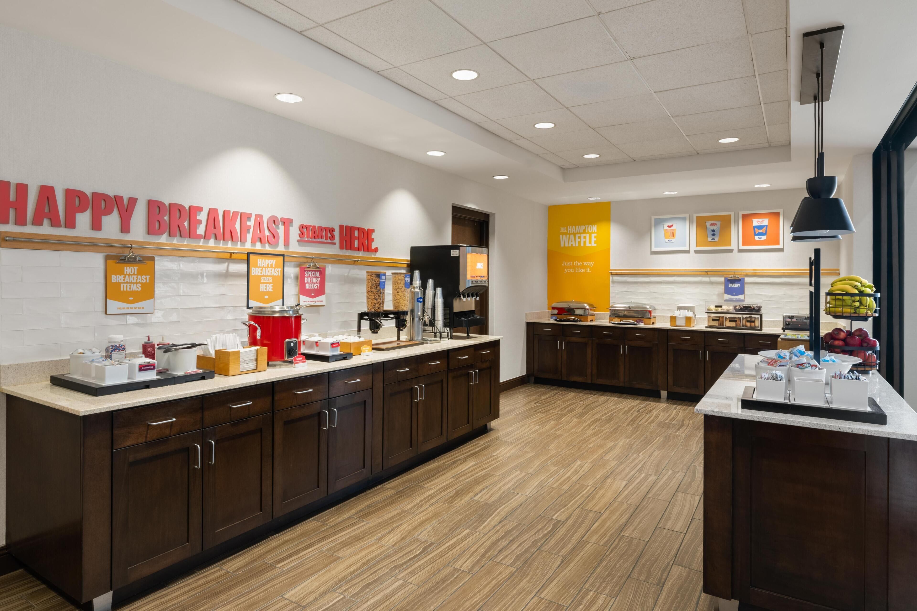 A breakfast area with a sign reading 'HAPPY BREAKFAST STARTS HERE.'