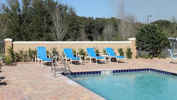 Una piscina al aire libre, sillones reclinables de piscina