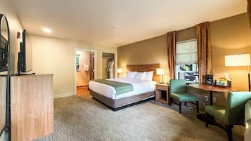 Habitación de hotel con cama, escritorio con silla, televisión y baño visible a través de una puerta abierta.