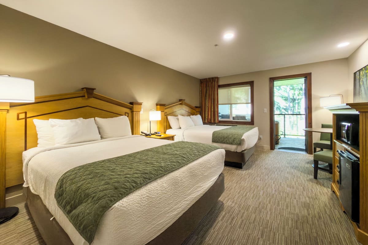 A hotel room with two beds, a desk, a chair, a television, and a window.