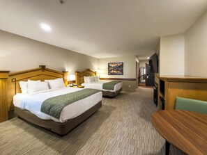 A hotel room with two beds, a desk, a chair, a TV, and a painting on the wall.